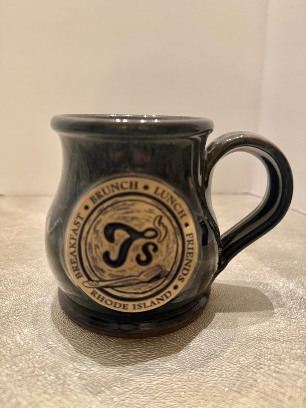 T’s Restaurant Deneen Pottery Dark Blue Ceramic Mug with Branded Emblem.